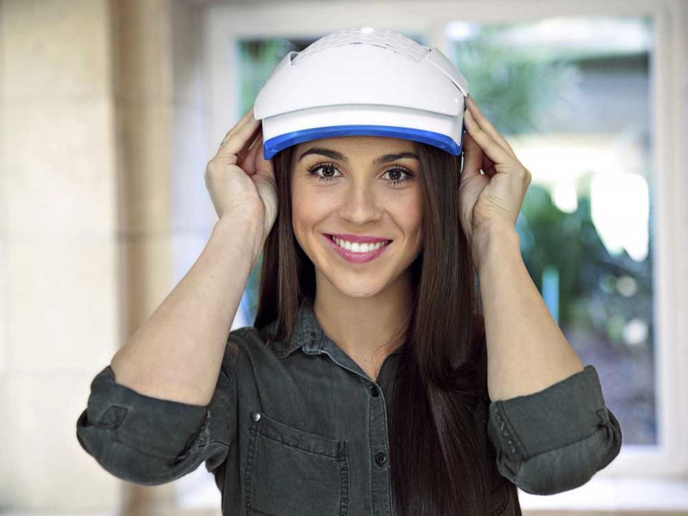 An image of a woman usinga Theradone Laser Light Therapy helmet